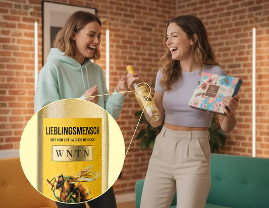 Zwei Freundinnen freuen sich über eine Geschenkbox und eine Flasche WNTN-Wein